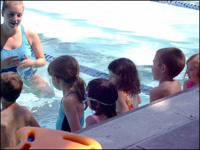 The class of seven children assemble on the water table
