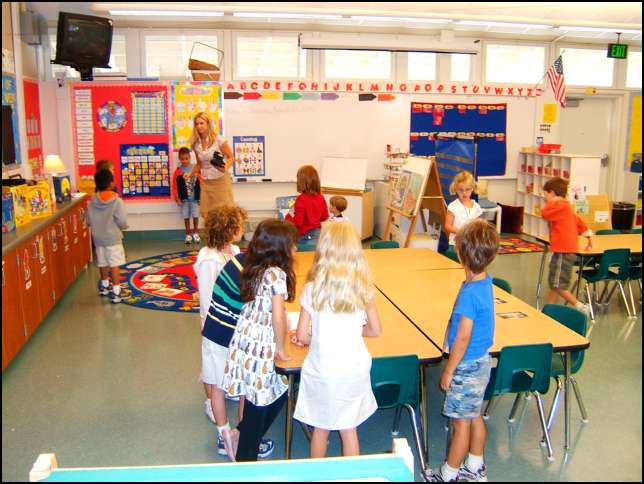 Kids gather around a large piece of paper to write their name
