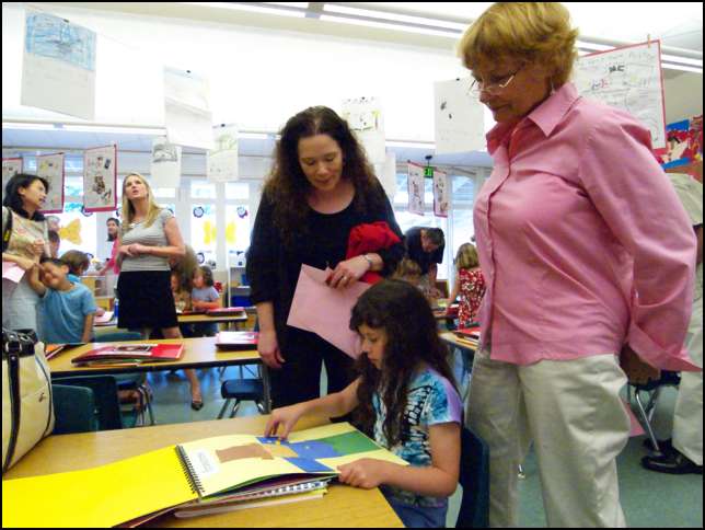 Sydney showing Linda and Sirpa here memory book of Kindergarten in Room 7 with Miss Tyler